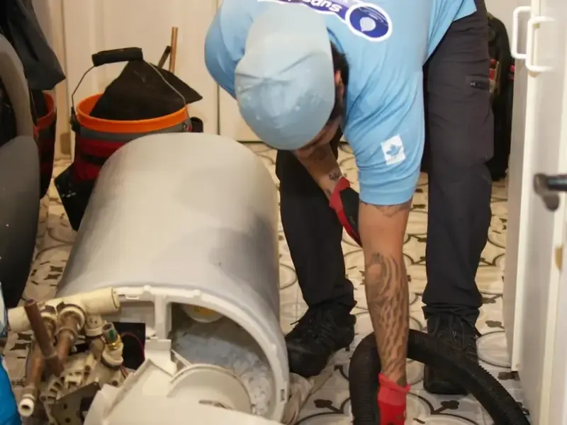 Technician vacuum-cleaning loose resin from inside opened softener body during repair service call